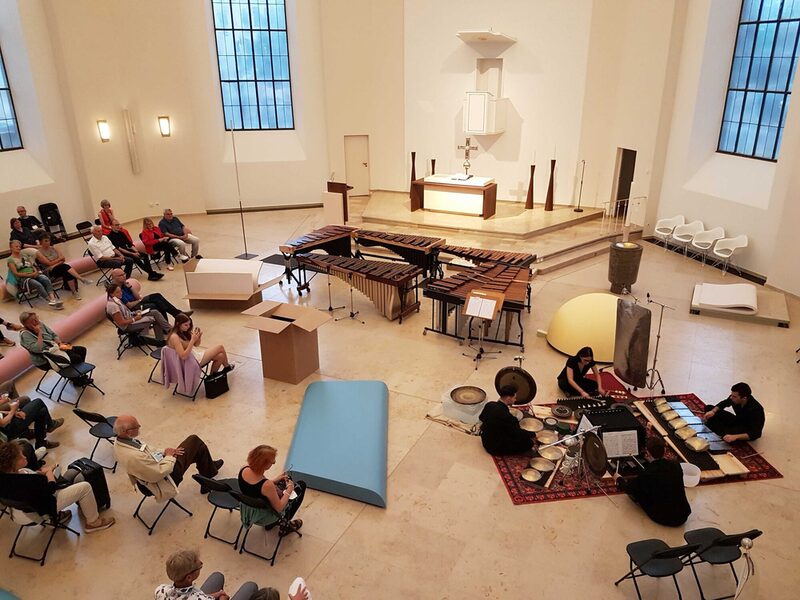 Menschen im Kirchenraum der Karlskirche die musizieren oder zuhören